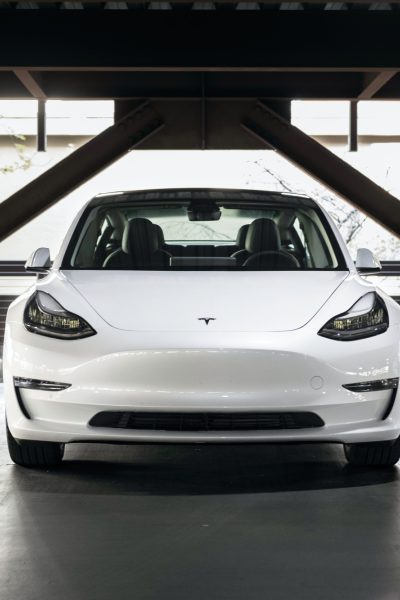 White Tesla in multistory car park with blurred out registration